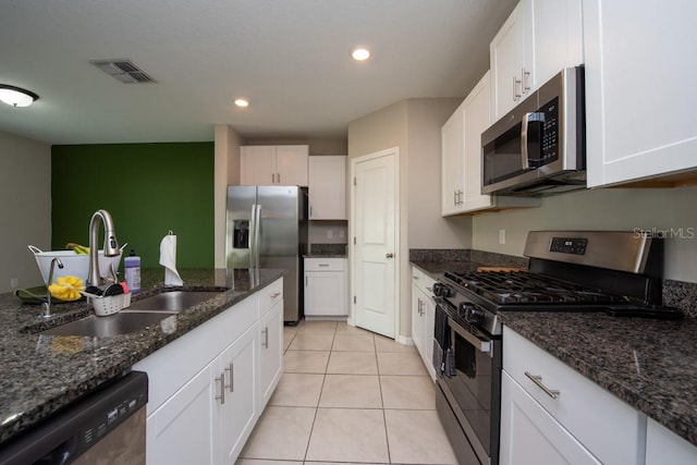 kitchen featuring dark stone counters, white cabinetry, sink, and stainless steel appliances