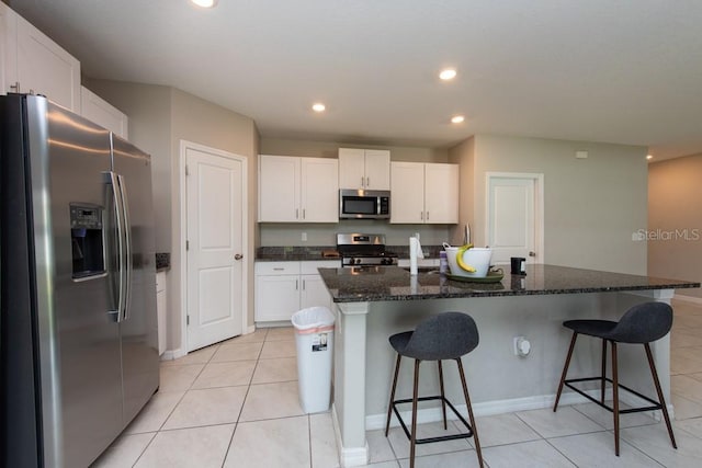 kitchen featuring stainless steel appliances, white cabinetry, and a center island with sink