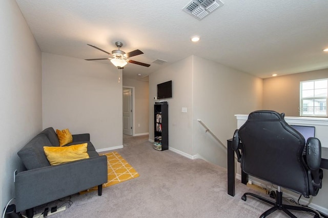 carpeted office space with a textured ceiling and ceiling fan