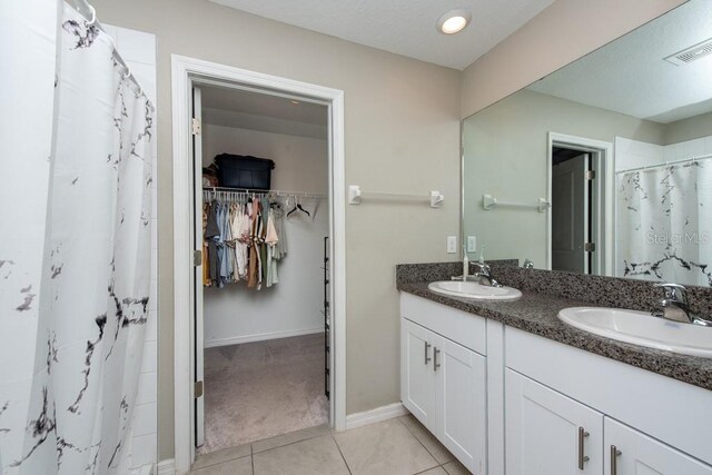10348 Blue Plume Ct, Riverview, FL 33578 - bathroom featuring double vanity, a spacious closet, tile patterned floors, curtained shower, and baseboards