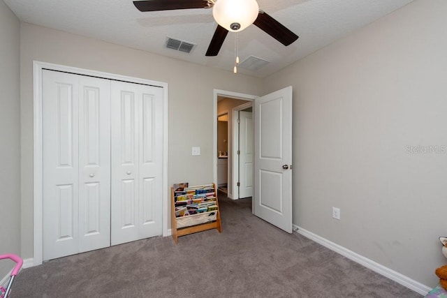 carpeted bedroom with ceiling fan, a closet, and a textured ceiling