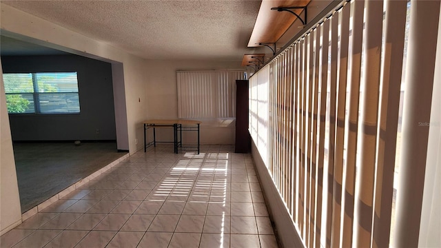 carpeted empty room with a textured ceiling and tile patterned floors