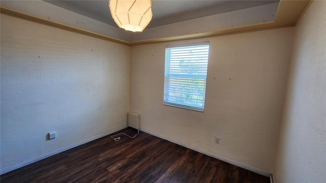 unfurnished room featuring baseboards and dark wood finished floors