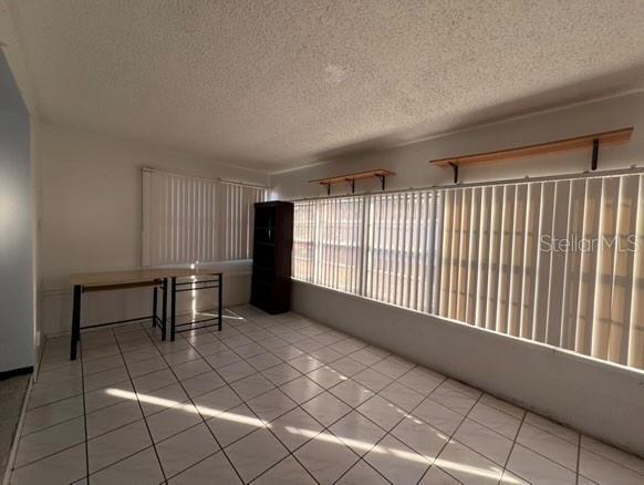 tiled empty room with a textured ceiling