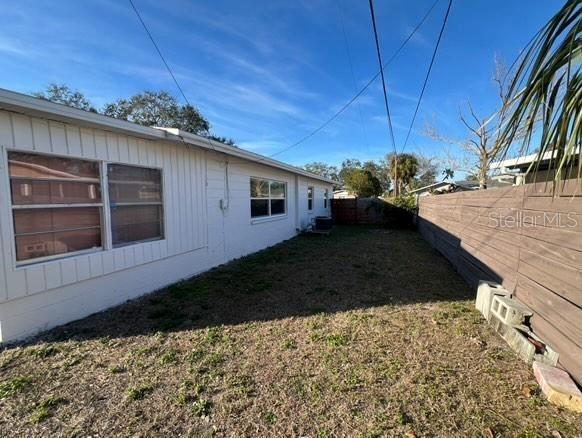 view of side of property featuring central air condition unit, a fenced backyard, and a yard