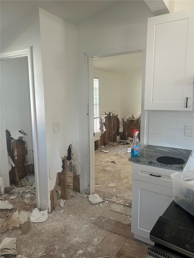 kitchen with white cabinetry, backsplash, and dark stone countertops