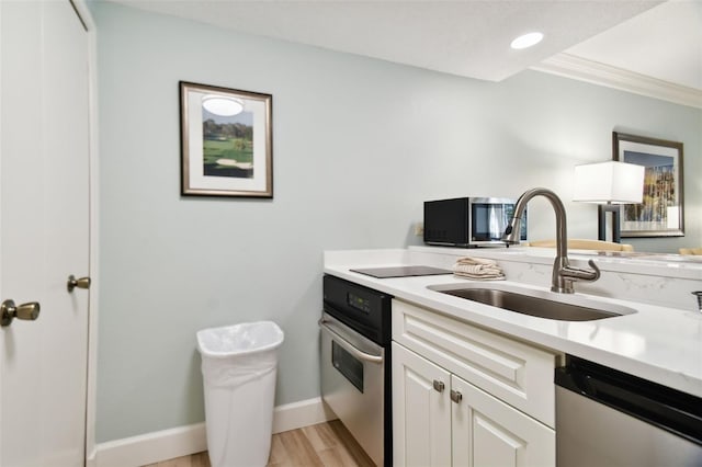 kitchen with sink, white cabinetry, stainless steel appliances, ornamental molding, and light hardwood / wood-style flooring