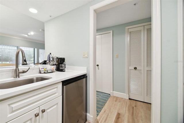 kitchen with stainless steel dishwasher, sink, white cabinetry, and light hardwood / wood-style flooring