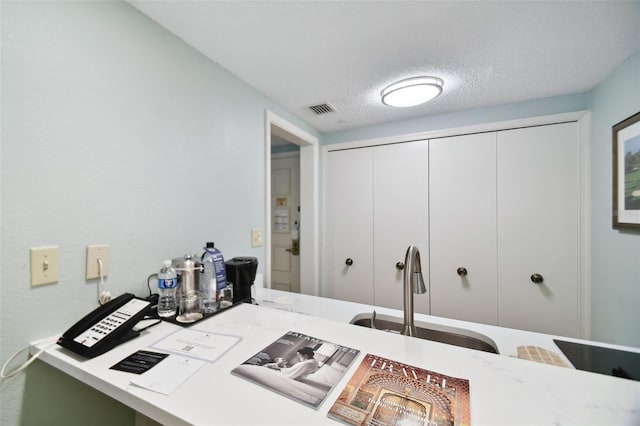 kitchen with sink, white cabinets, and a textured ceiling