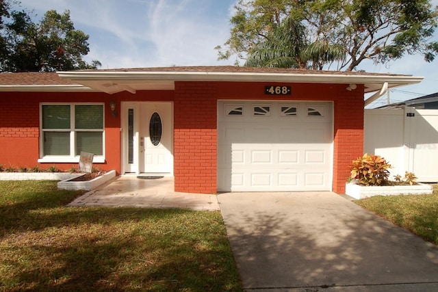 ranch-style home with a front yard, brick siding, driveway, and an attached garage