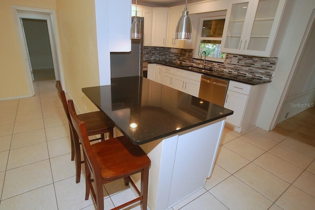 kitchen with sink, stainless steel dishwasher, backsplash, a breakfast bar area, and white cabinets