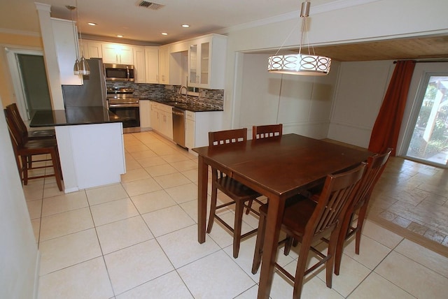 dining space with sink, light tile patterned floors, and ornamental molding