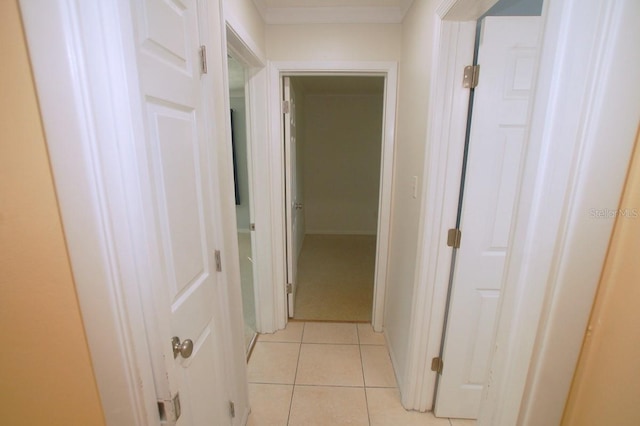 hallway featuring light tile patterned floors and ornamental molding