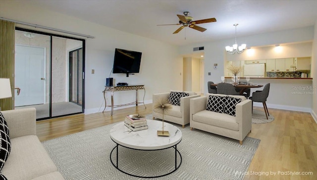 living room featuring ceiling fan with notable chandelier and light hardwood / wood-style floors