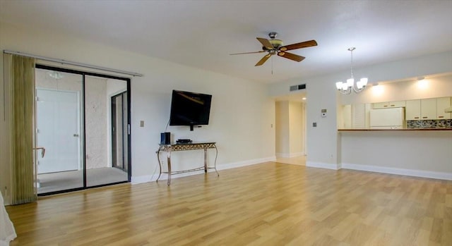 unfurnished living room featuring ceiling fan with notable chandelier and light hardwood / wood-style floors