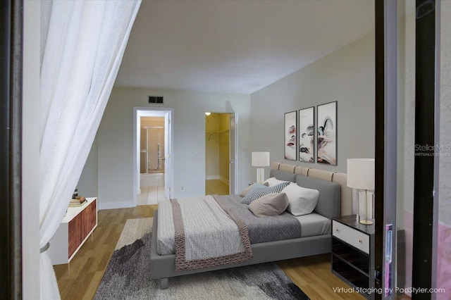 bedroom with a walk in closet, ensuite bathroom, a closet, and light wood-type flooring