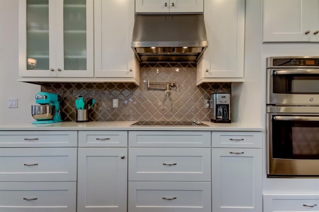 kitchen with white cabinets, stainless steel double oven, and wall chimney exhaust hood