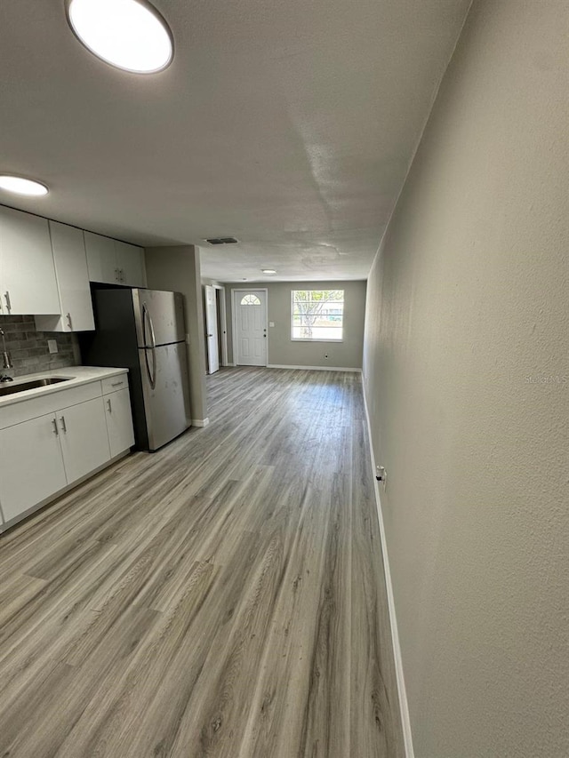 5928 13th Street Ct E, Bradenton, FL 34203 - kitchen featuring a sink, freestanding refrigerator, baseboards, backsplash, and white cabinetry