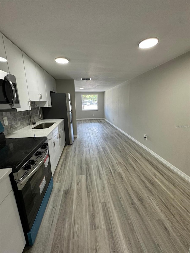 5928 13th Street Ct E, Bradenton, FL 34203 - kitchen featuring white cabinets, light wood-style floors, range with electric cooktop, stainless steel microwave, and baseboards