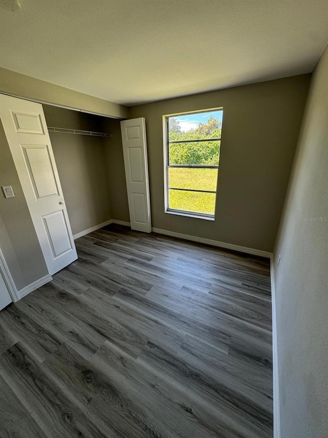 5928 13th Street Ct E, Bradenton, FL 34203 - unfurnished bedroom featuring dark wood-type flooring, a closet, and baseboards