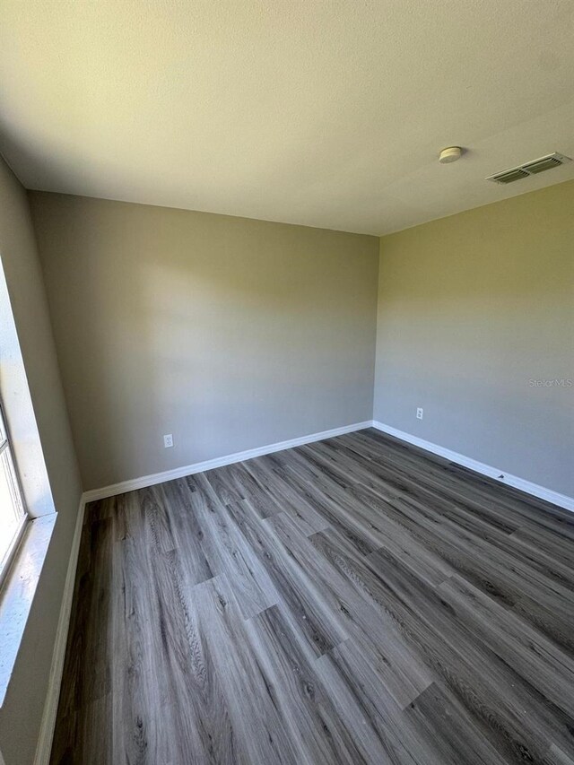 5928 13th Street Ct E, Bradenton, FL 34203 - unfurnished room with a textured ceiling, visible vents, baseboards, and dark wood-style flooring