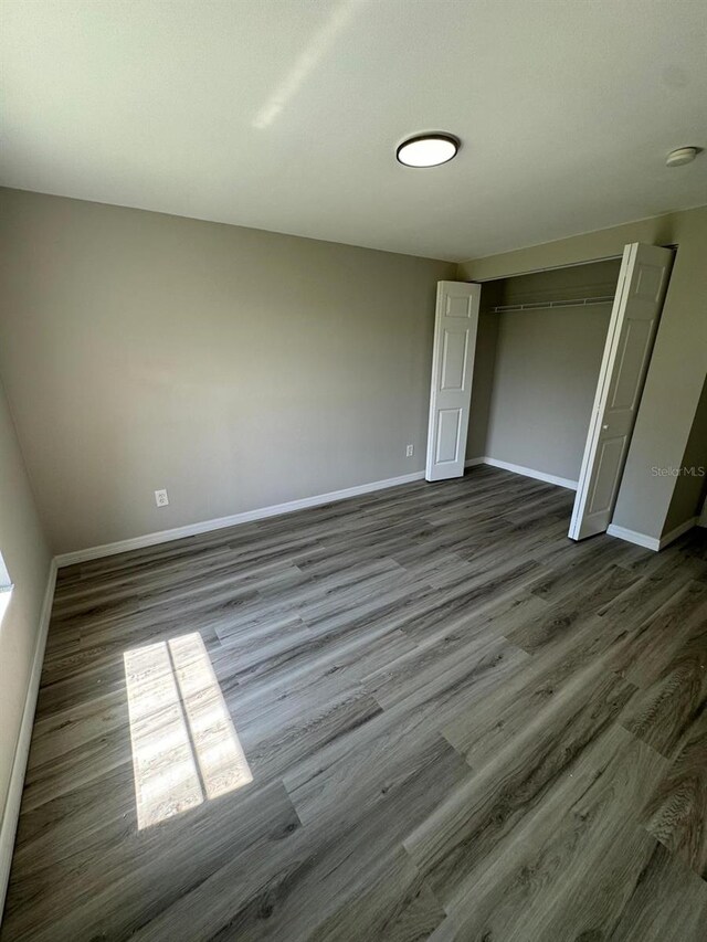 5928 13th Street Ct E, Bradenton, FL 34203 - unfurnished bedroom with baseboards, a closet, and dark wood-style flooring