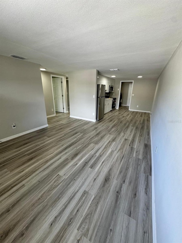 5928 13th Street Ct E, Bradenton, FL 34203 - unfurnished living room featuring visible vents, wood finished floors, baseboards, and a textured ceiling