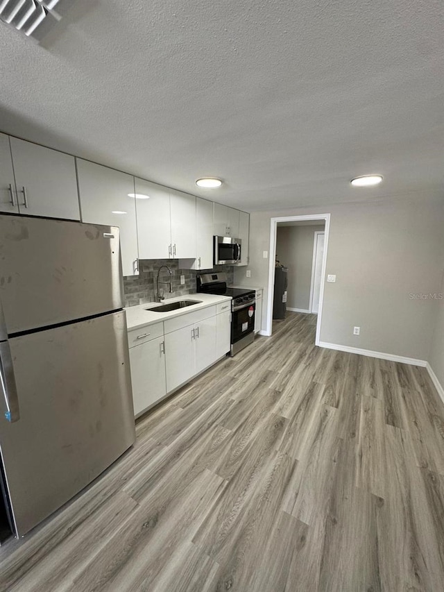 5928 13th Street Ct E, Bradenton, FL 34203 - kitchen featuring appliances with stainless steel finishes, a sink, white cabinetry, and light wood-type flooring