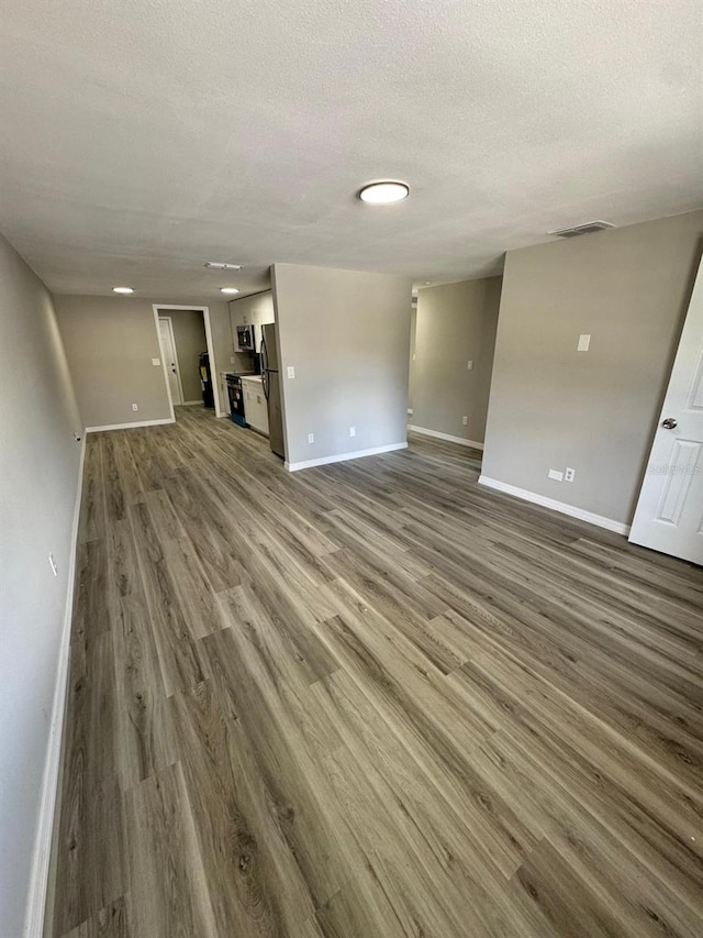 5928 13th Street Ct E, Bradenton, FL 34203 - unfurnished living room with a textured ceiling, wood finished floors, visible vents, and baseboards