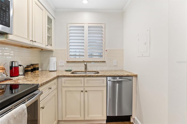 kitchen with backsplash, appliances with stainless steel finishes, light stone countertops, crown molding, and sink