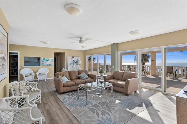 living room featuring ceiling fan, wood-type flooring, and a textured ceiling