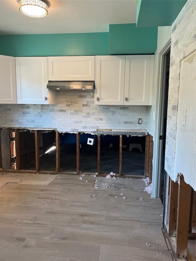 kitchen featuring white cabinets, exhaust hood, light hardwood / wood-style flooring, and tasteful backsplash