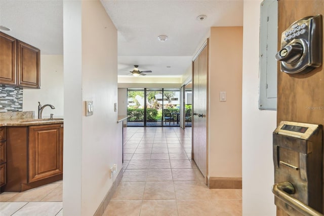 hall with a textured ceiling, electric panel, sink, and light tile patterned floors