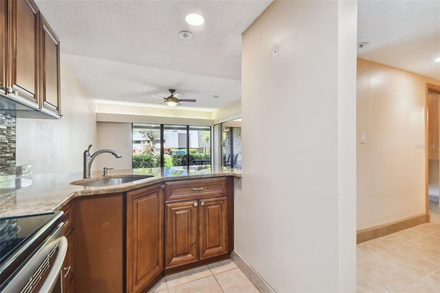 kitchen with sink, light stone countertops, kitchen peninsula, and light tile patterned floors