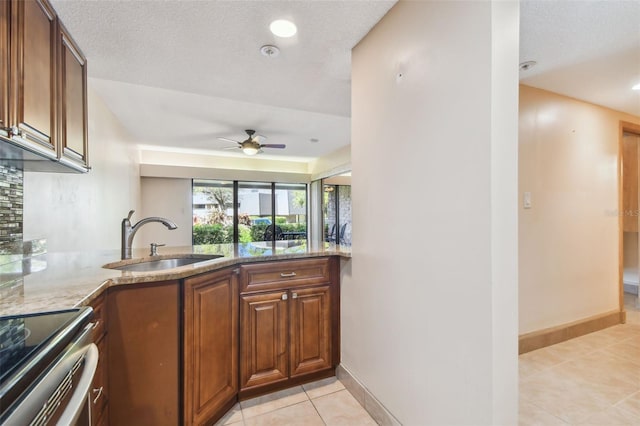 36750 US Highway 19 N Unit 19106, Palm Harbor, FL 34684 - kitchen featuring a sink, light tile patterned flooring, light stone countertops, a ceiling fan, and baseboards