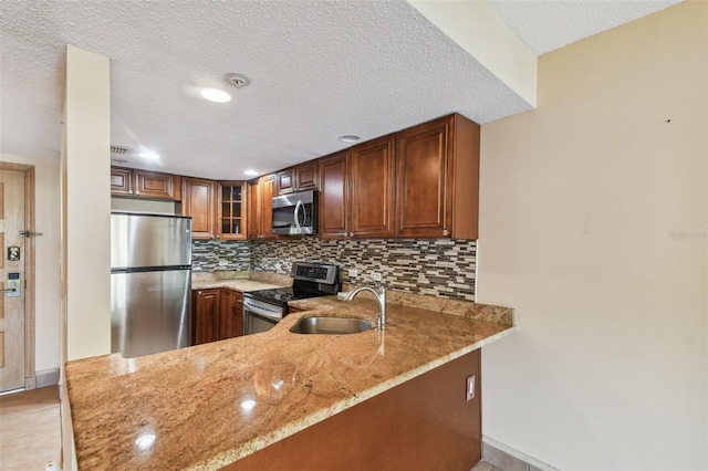 kitchen with light stone counters, stainless steel appliances, sink, and kitchen peninsula