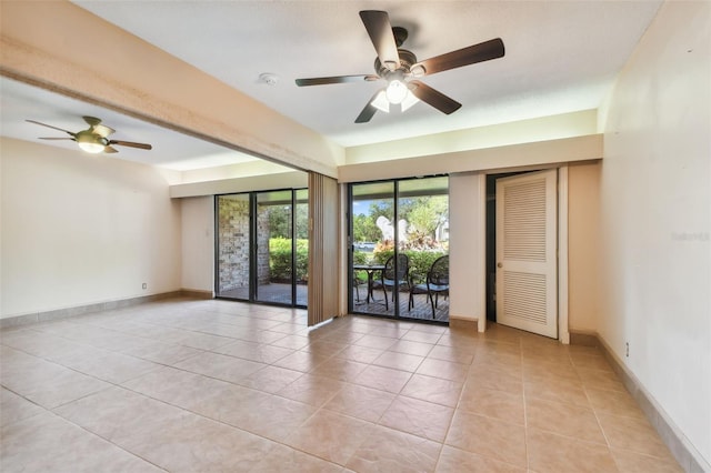 empty room with ceiling fan and light tile patterned floors