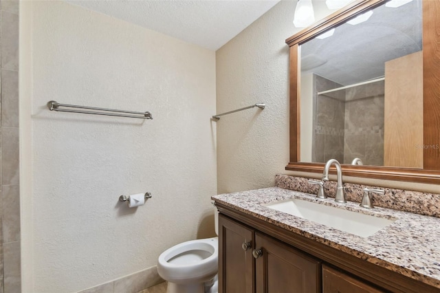 bathroom featuring vanity, a shower, a textured ceiling, and toilet