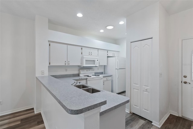 kitchen featuring dark wood-type flooring, white appliances, light countertops, and a sink