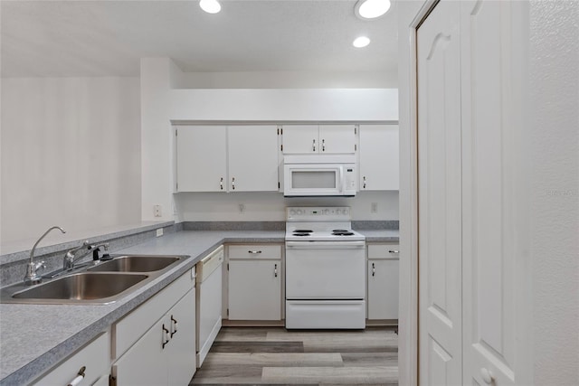 kitchen featuring white appliances, white cabinets, light wood-type flooring, a sink, and recessed lighting