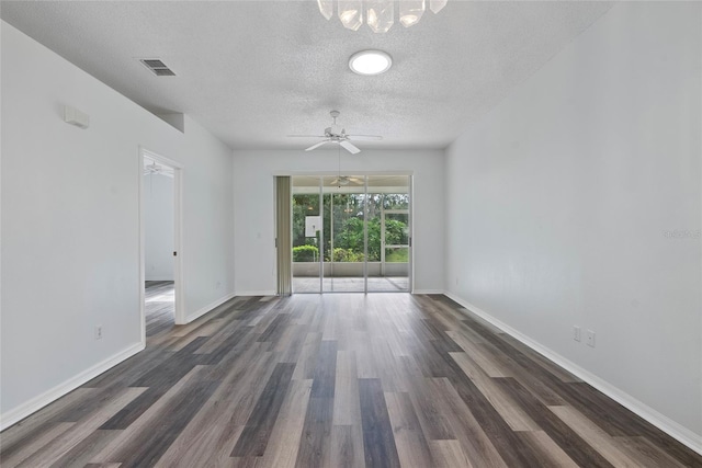 spare room with a textured ceiling, dark wood finished floors, visible vents, and baseboards