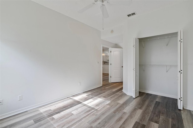 unfurnished bedroom with a closet, wood finished floors, visible vents, and baseboards