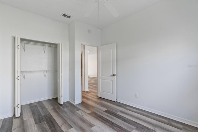 unfurnished bedroom featuring a closet, visible vents, baseboards, and wood finished floors