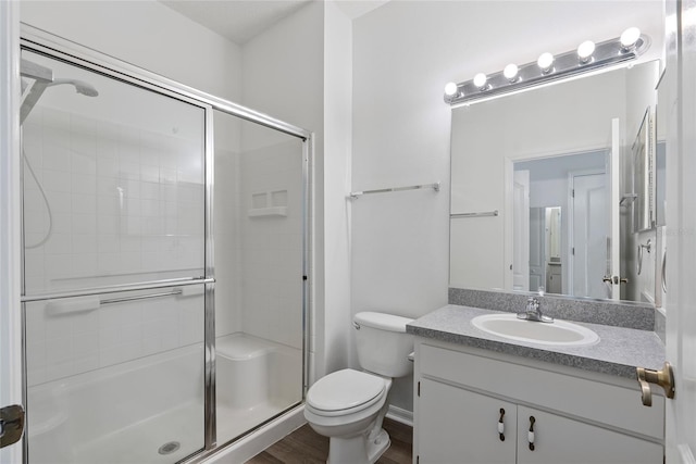 bathroom featuring vanity, a stall shower, wood finished floors, and toilet