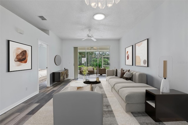 living room with visible vents, ceiling fan, a textured ceiling, wood finished floors, and baseboards