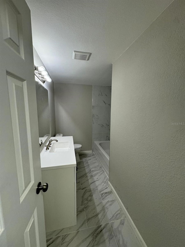 bathroom featuring vanity, a bathtub, a textured ceiling, and toilet