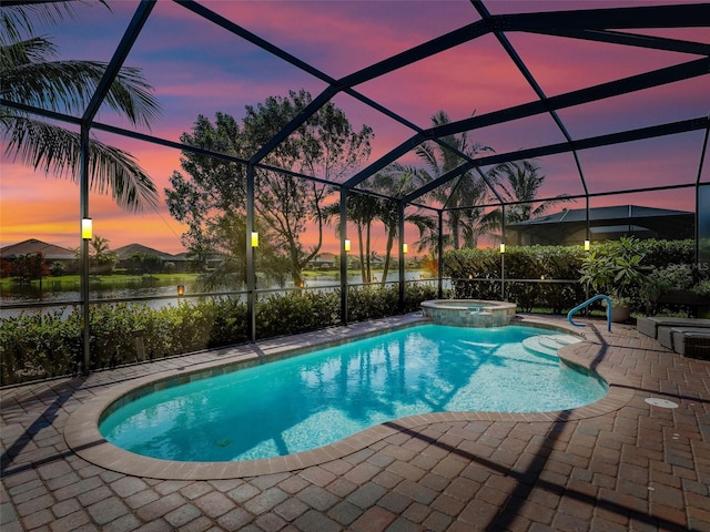 pool at dusk featuring a patio area, a lanai, an in ground hot tub, and a water view