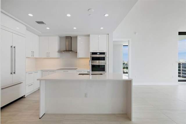 kitchen with plenty of natural light, white cabinetry, wall chimney range hood, and paneled built in refrigerator