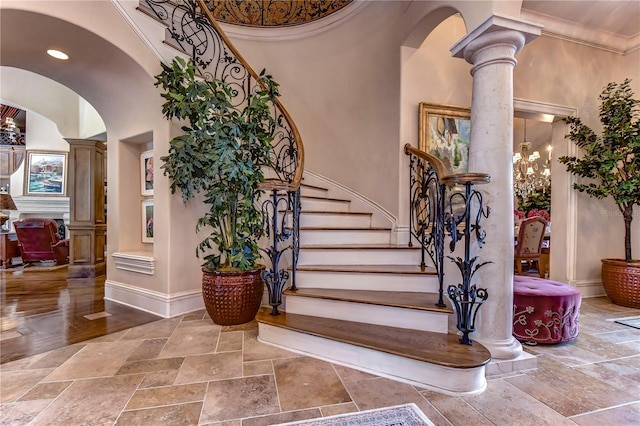 stairs featuring decorative columns, crown molding, and a towering ceiling