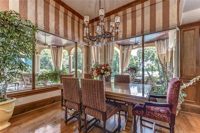 dining space with plenty of natural light, hardwood / wood-style flooring, and ceiling fan with notable chandelier